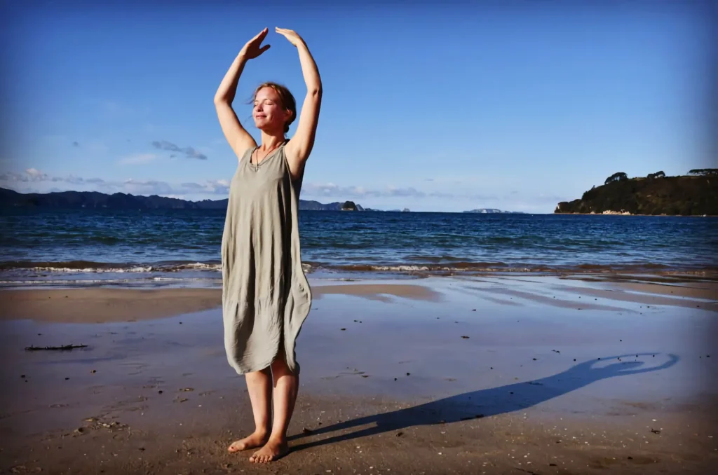 Frau in Yuang Gong Pose am Strand